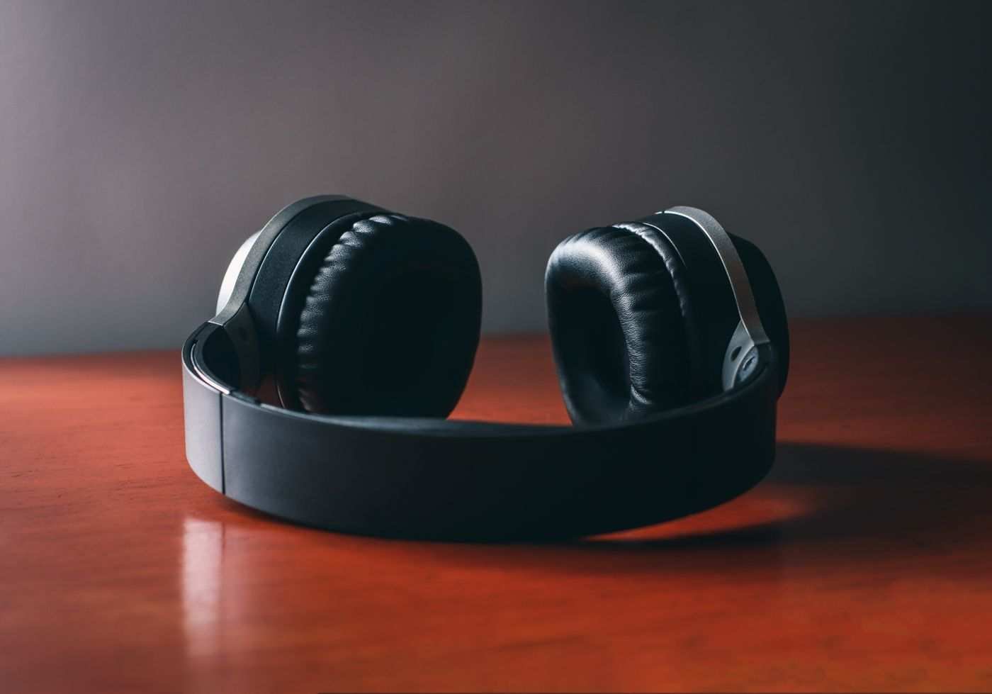 A pair of black over-ear headphones resting on a wooden desk